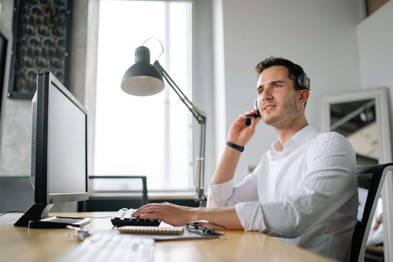 our-stories Male call center agent with headset working at desk, providing excellent customer service.